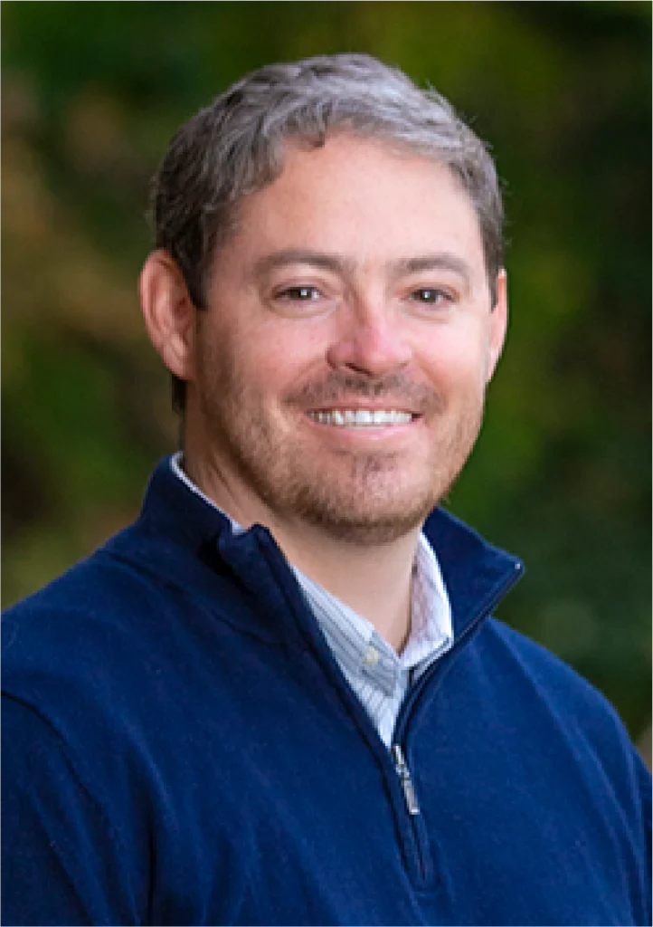 A man in blue jacket smiling for the camera.