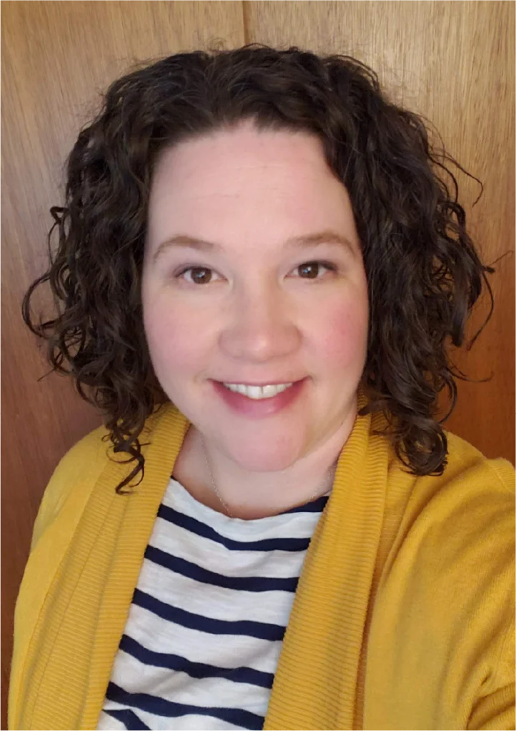 A woman with curly hair wearing a yellow jacket.