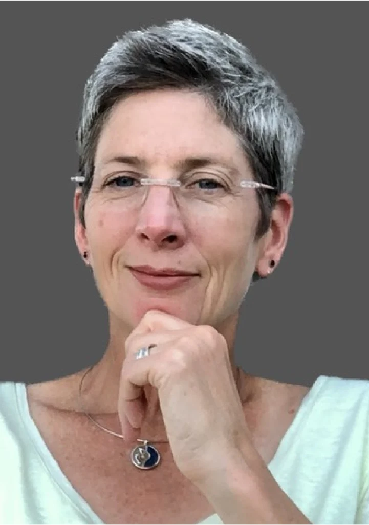 A woman with glasses and short hair is posing for the camera.