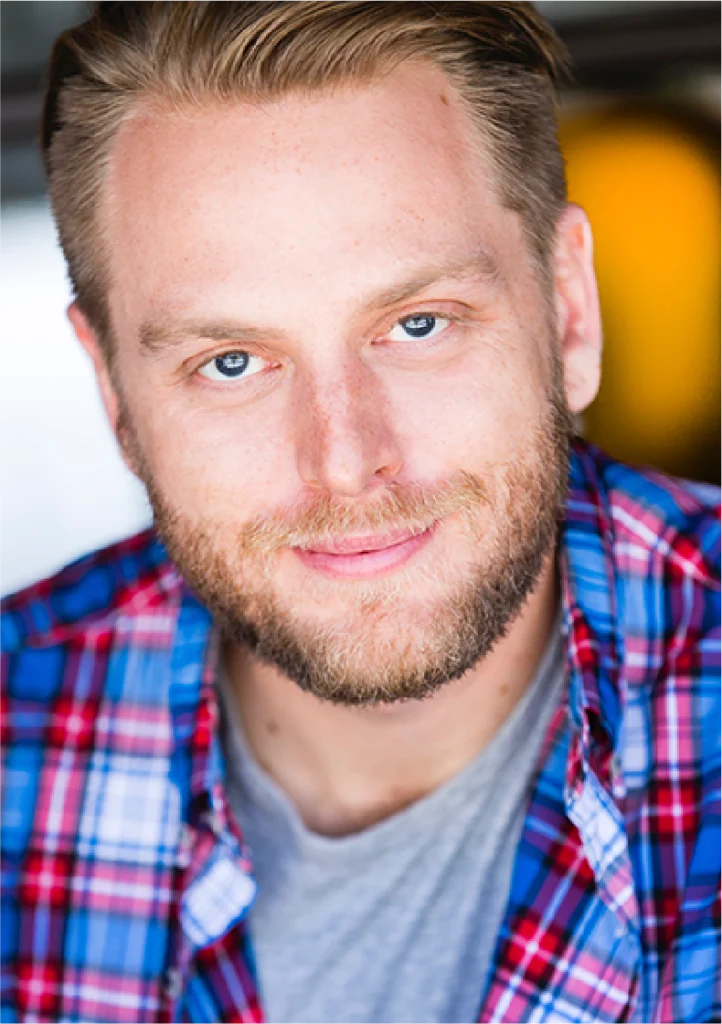 A man with beard and plaid shirt smiling for the camera.